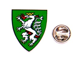 Grünes Wappen mit weißem Löwen und rotem Helm sowie runde Metallplakette mit Adlermotiv daneben.